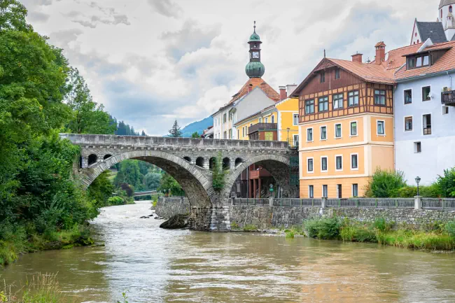 Arch-Brücke über den Fluss Mur in der historischen Stadt Murau in den zentralen Ostalpen, Österreich